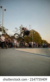 Kyiv, Ukraine - September 12, 2021: Extreme Cyclist Performs Tricks In The Skate Park. Extreme Sport. Crowded Skatepark. A Group Of Guys Show Tricks On The Ramp. BMX Tricks.