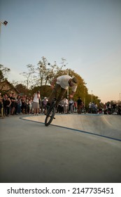 Kyiv, Ukraine - September 12, 2021: Extreme Cyclist Performs Tricks In The Skate Park. Extreme Sport. Crowded Skatepark. A Group Of Guys Show Tricks On The Ramp. BMX Tricks.