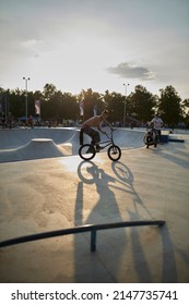 Kyiv, Ukraine - September 12, 2021: Extreme Cyclist Performs Tricks In The Skate Park. Extreme Sport. Crowded Skatepark. A Group Of Guys Show Tricks On The Ramp. BMX Tricks.