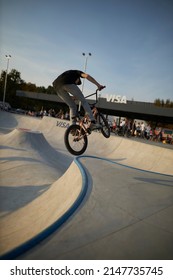 Kyiv, Ukraine - September 12, 2021: Extreme Cyclist Performs Tricks In The Skate Park. Extreme Sport. Crowded Skatepark. A Group Of Guys Show Tricks On The Ramp. BMX Tricks.