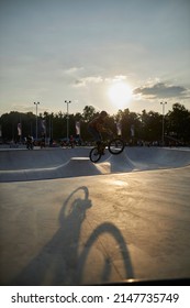 Kyiv, Ukraine - September 12, 2021: Extreme Cyclist Performs Tricks In The Skate Park. Extreme Sport. Crowded Skatepark. A Group Of Guys Show Tricks On The Ramp. BMX Tricks.