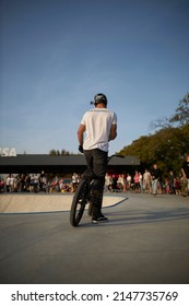 Kyiv, Ukraine - September 12, 2021: Extreme Cyclist Performs Tricks In The Skate Park. Extreme Sport. Crowded Skatepark. A Group Of Guys Show Tricks On The Ramp. BMX Tricks.