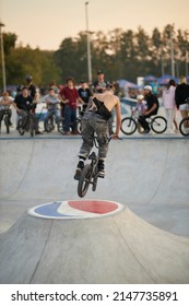 Kyiv, Ukraine - September 12, 2021: Extreme Cyclist Performs Tricks In The Skate Park. Extreme Sport. Crowded Skatepark. A Group Of Guys Show Tricks On The Ramp. BMX Tricks.