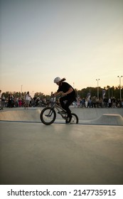 Kyiv, Ukraine - September 12, 2021: Extreme Cyclist Performs Tricks In The Skate Park. Extreme Sport. Crowded Skatepark. A Group Of Guys Show Tricks On The Ramp. BMX Tricks.