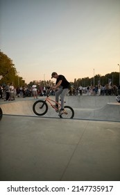 Kyiv, Ukraine - September 12, 2021: Extreme Cyclist Performs Tricks In The Skate Park. Extreme Sport. Crowded Skatepark. A Group Of Guys Show Tricks On The Ramp. BMX Tricks.