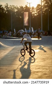 Kyiv, Ukraine - September 12, 2021: Extreme Cyclist Performs Tricks In The Skate Park. Extreme Sport. Crowded Skatepark. A Group Of Guys Show Tricks On The Ramp. BMX Tricks.