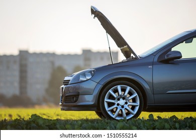 Kyiv, Ukraine - September 16, 2019: Car with open hood on empty gravel field road on blurred bright sky copy space background. 