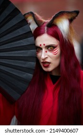Kyiv, Ukraine September 4: Comic Con 2021, fandom festival in Kyiv, Ukraine. Cosplayers dressed as superheroes. Girl cosplayer in the image of a Kitsune fox, in a red kimono with a black fan.
