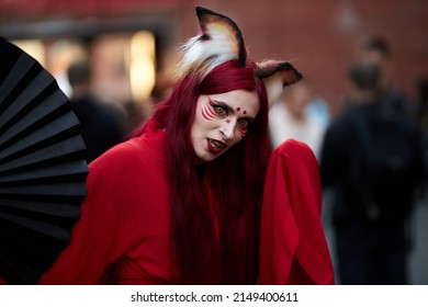 Kyiv, Ukraine September 4: Comic Con 2021, fandom festival in Kyiv, Ukraine. Cosplayers dressed as superheroes. Girl cosplayer in the image of a Kitsune fox, in a red kimono with a black fan.