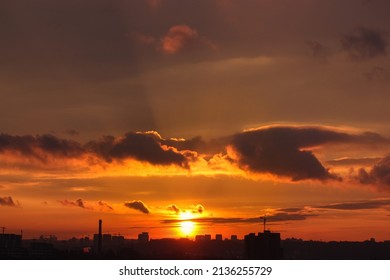 Kyiv, Ukraine. Silhouettes Of Houses Against Red-orange Sky At Sunset. City Urban Landscape. Contrasting Clouds At Sunset. The Sun Is Setting Behind The Horizon. Sunlight Breaking Through The Clouds.