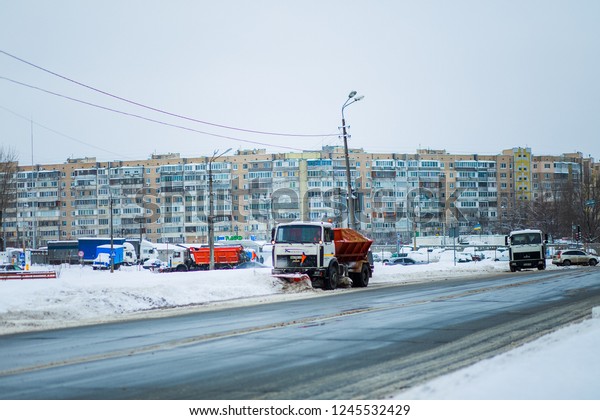 Kyiv,\
Ukraine-25.12.17: Snow plow clears roads in city after heavy winter\
snowfall blizzard for vehicle access. Big orange car across the\
road. Deep snow Clean road without\
accidents.