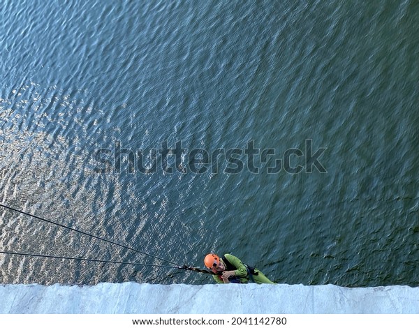 Kyiv\
Ukraine-September 2021: Rope jumping extreme jumping from bridge.\
Young woman is engaged in extreme sports, jumping from bridge over \
Dnieper river. Bungee jumping\
attraction.