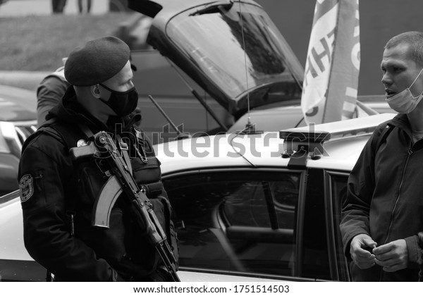 Kyiv/Ukraine - 05.29.2020: ukrainian police man in\
uniform and with the gun kalashnikov near the service car during\
the protest rally