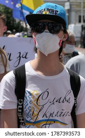 Kyiv/Ukraine - 07.16.2020: Young Tall Man With Backpack, Blue Cap With Visor, Sunglasses And Medical Mask Due To Coronavirus Inside Protesters Crowd With Banners For Ukrainian Language Protection