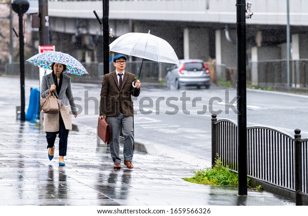 Kyoto, Japan -\
April 9, 2019: Gojo-dori street during rainy day and people walking\
holding umbrellas on\
sidewalk