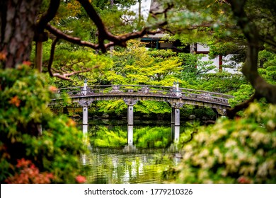 Kyoto, Japan framing view of green spring garden in Imperial Palace with water reflection and stone bridge on peaceful lake pond