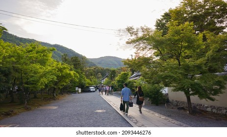 Kyoto, Japan - May 2014: Asian Couple Walking On Stone Pathway In Zen Garden Of Tenryuji Temple In Arashiyama With Mountains And Bright Sky Background.