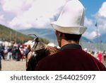 A Kyrgyz eagle hunter wearing traditional clothing holds a hooded eagle on his arm during the World Nomad Games in Kyrgyzstan, 2016.