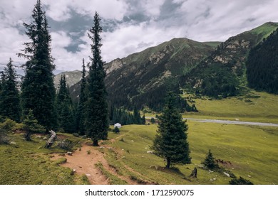 Kyrgyzstan. Karakol. Alakel. Karakol Gorge. In The Distance Stands A White Yurt Against A Background Of Mountains. Summer