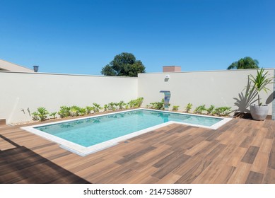 "L" shaped pool design in modern residence. Swimming pool with solar heating, clear and bluish on a sunny day. Ceramic floor with wood texture. Swimming pool with artificial metal waterfall. - Powered by Shutterstock