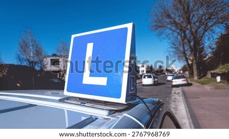 L sign or a Learner Driver sign on top of a driving school car parked on the street.