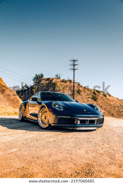 LA, CA, USA\
August 12,\
2022\
Porsche Turbo S parked on dirt with a power line in the\
background
