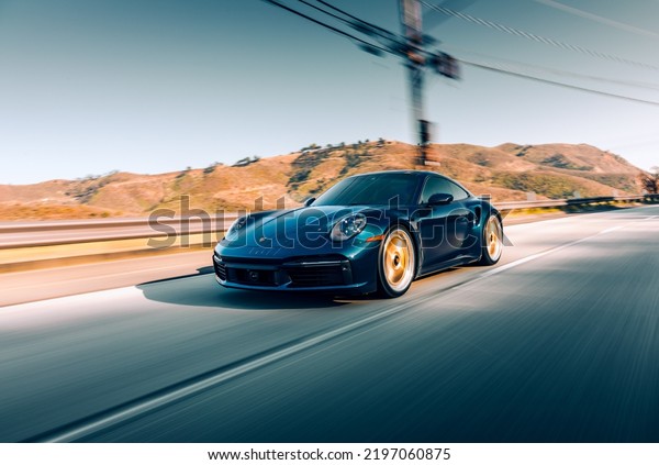 LA, CA,\
USA\
August 12, 2022\
Porsche Turbo S driving on the street by\
itself with mountains in the\
background