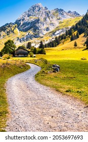 La Clusaz, France - August 20 2020 : the gravel road to a historic wooden farm on the alpine meadows in the french alps