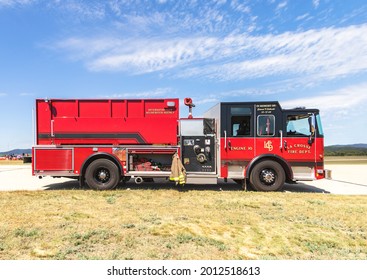 La Crosse, WI, USA - June 13, 2021: Side view of prepared equipment and fire suit hanging on red firetruck park on the road, ready for emergency accident. Safety service and rescue at outdoor event