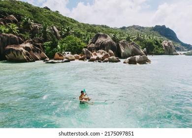 "La digue" island in Seychelles. Silver beach with granitic stone, and jungle. Man enjoying vacations on the beach and having fun with kayak. Aerial view shot with drone