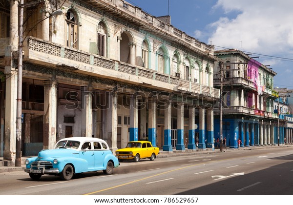 LA HAVANA, CUBA - 3th of June 2015: Typical\
american cars, blue and yellow in a street with traditional and\
colored arcades buildings