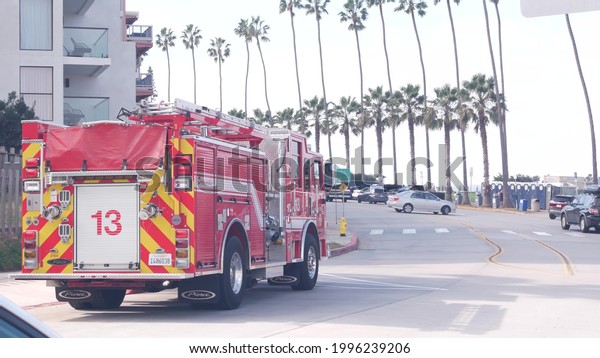 La Jolla, California USA - 23 Nov 2020: Red\
firefighters fire truck engine, emergency lifeguard vehicle or 911\
rescue firetruck in San Diego. Public safety car with firemen life\
guards and palm trees.