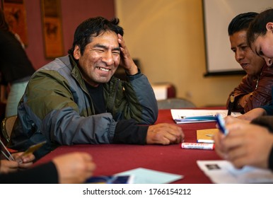 La Paz / Bolivia - December 17 2014: Man With Indigenous Features Laughs With His Group Of Friends At A Table With A Red Tablecloth