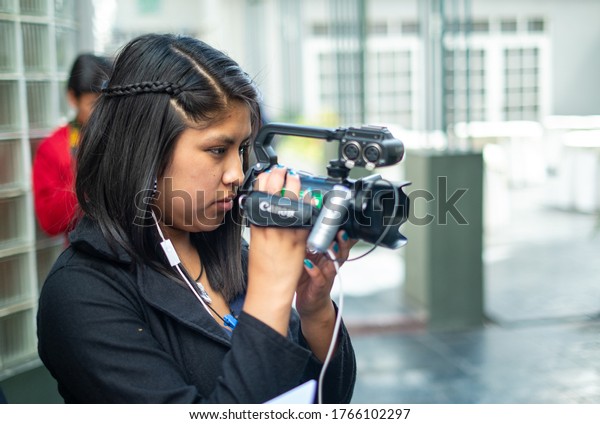 La Paz / Bolivia - December\
17 2014: Young Black Hair Hispanic Woman Films with a Canon\
Camcorder 
