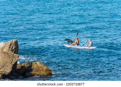 LA SPEZIA, ITALY - July 28, 2022: A Mature Couple And A Dog Aboard A Kayak, Paddling In The Blue Mediterranean Sea, On A Sunny Summer Day. Gulf Of La Spezia, Liguria, Italy, Europe.
