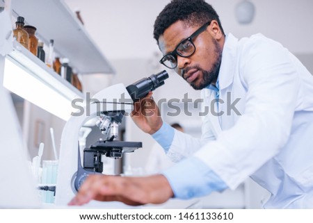 Lab assistant checking micro organisms through the microscope.