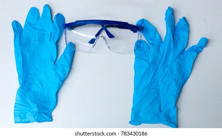 Lab gloves and safety goggles positioned to make it look like the glove is adjusting the glasses on a chemistry lab textured surface bench.
