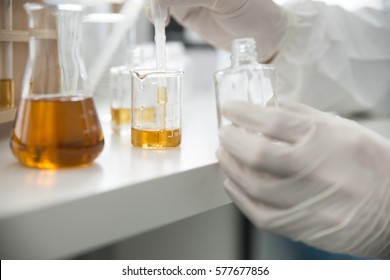 Lab / Laboratory closeup of hands in sterile gloves using a pipette to fill a glass bottle with liquid. Chemical worker, Chemistry, Experiment, Indicator, Vials, Erlenmeyer flask, Chemical laboratory.
