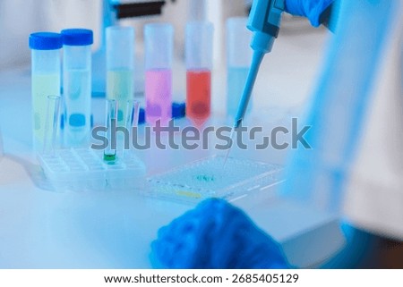 Lab scientist using precise digital pipette for measuring liquid volume in biology, chemistry, or medicine, dripping fluid to test tubes.