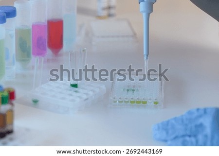 Lab scientist using precise digital pipette for measuring liquid volume in biology, chemistry, or medicine, dripping fluid to test tubes.