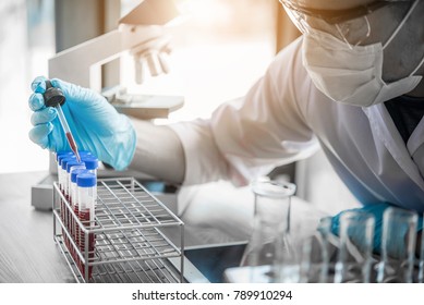 lab technician assistant analyzing a blood sample in test tube at laboratory. Medical, pharmaceutical and scientific research and development concept.