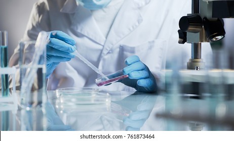 Lab technician checking material by creating chemical reaction with reagents - Powered by Shutterstock