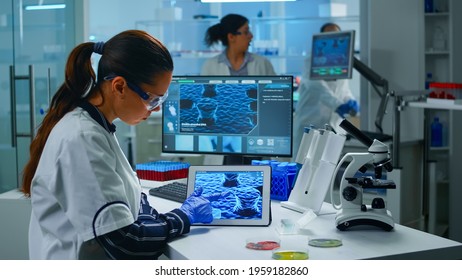 Lab Technician Doctor Analyzing Virus Evolution Looking On Digital Tablet. Team Of Scientists Conducting Vaccine Development Using High Tech For Researching Treatment Against Covid19 Pandemic.