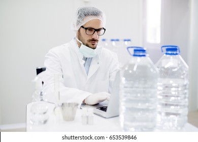 Lab Technician Doing Water Analysis, Dressed In Protective Sterile Equipment. Drinking Water Production.