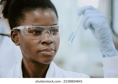 Lab technician examining test tube with protective glasses during chemical process. Showing focus and precision while handling delicate lab instruments with clear safety measures - Powered by Shutterstock