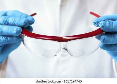 Lab Technician Holding A Pair Of Protective Goggles / Scientist Putting On Safety Goggles To Start A Job