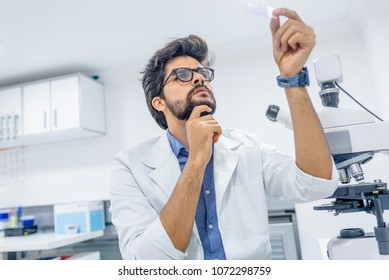 Lab technician looking at samples very focused holding the samples up close to him. Scientist looking at the scientific sample in the CDC laboratory