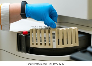 Lab technician processing samples in a centrifuge. A lab technician in blue gloves loads test tubes into a centrifuge for processing at a laboratory. - Powered by Shutterstock