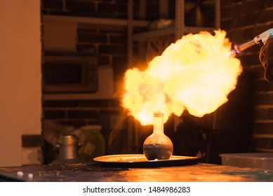 Lab technician setting fire to a ball with hydrogen blowtorch - Powered by Shutterstock