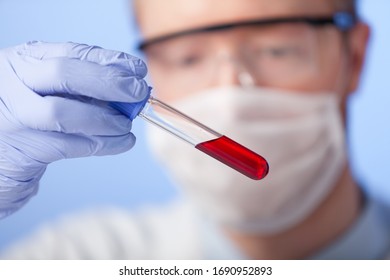 Lab. A Lab Technician In A White Coat, Rubber Gloves And Protective Glasses Checks The Behavior Of The Substance In A Closed Environment.